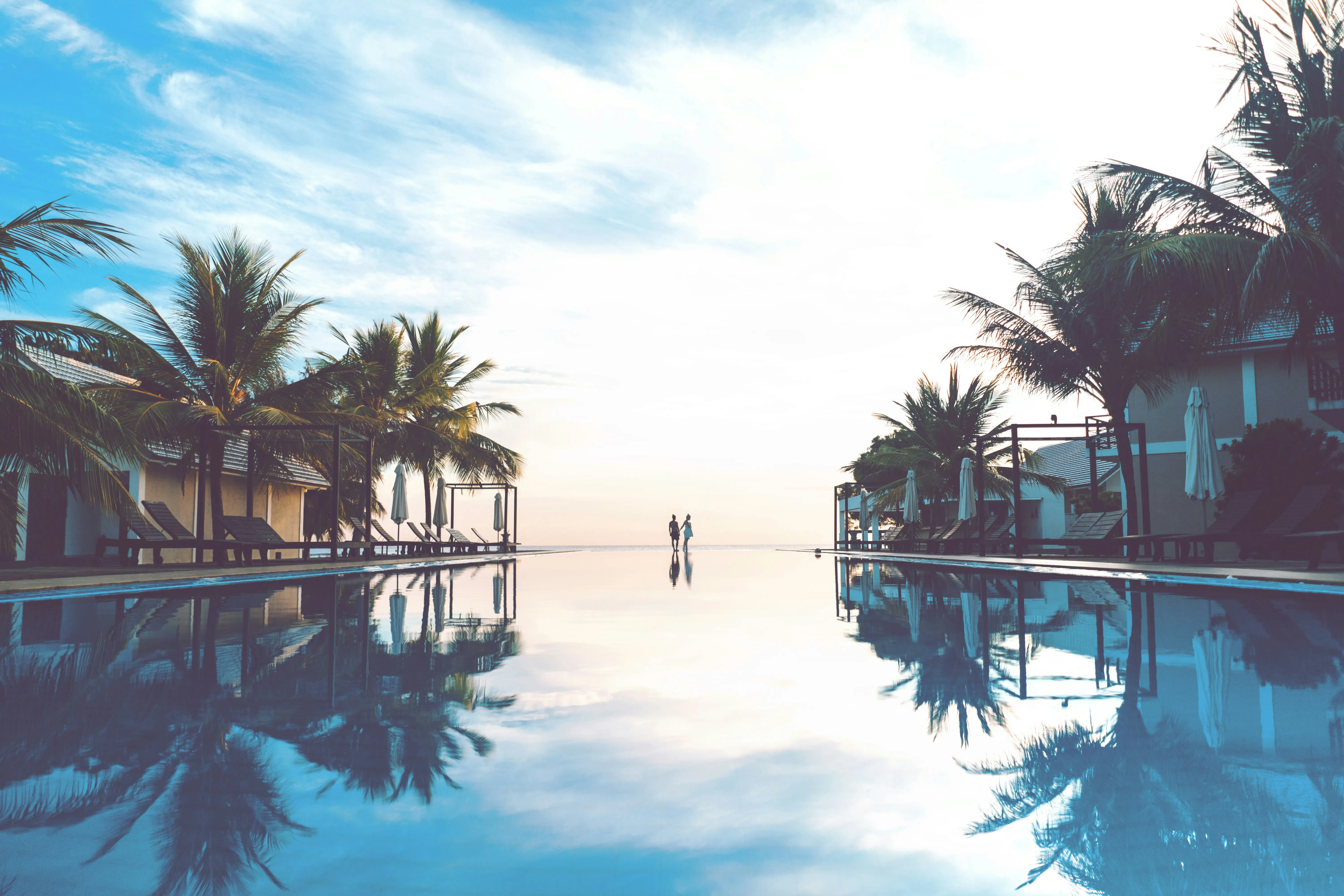 Casal ao amanhecer na borda de uma piscina de borda infinita à beira-mar